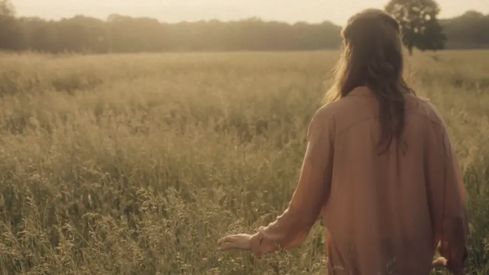 Une femme marche dans un champ au coucher du soleil lors de la production d'un film publicitaire pour Siemens.