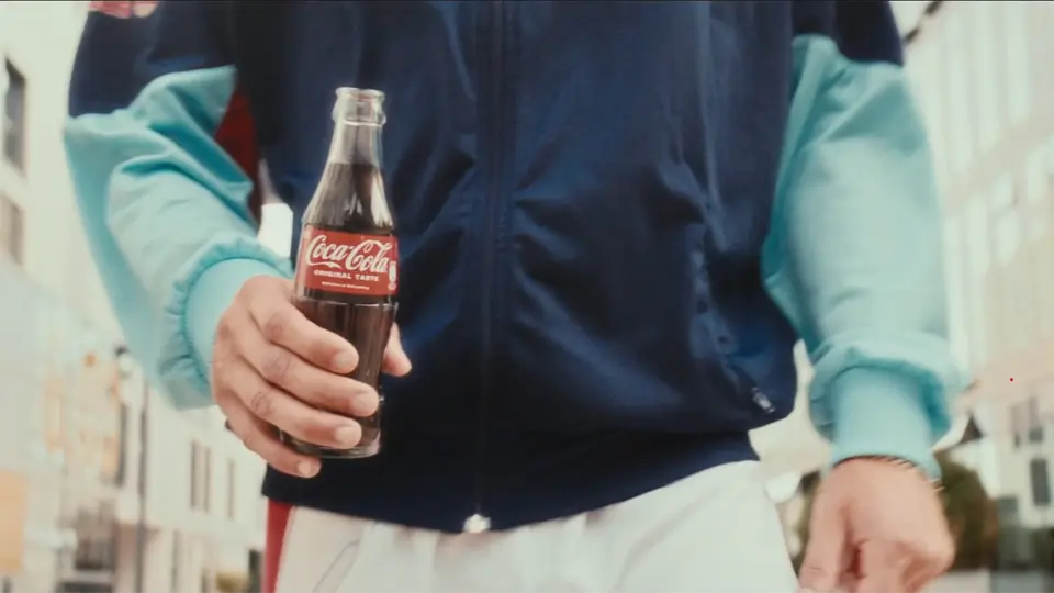 Ein Ausschnitt aus der Werbefilmproduktion in Köln, wo ein Mann durch die Stadt mit Flasche Coca Cola läuft.