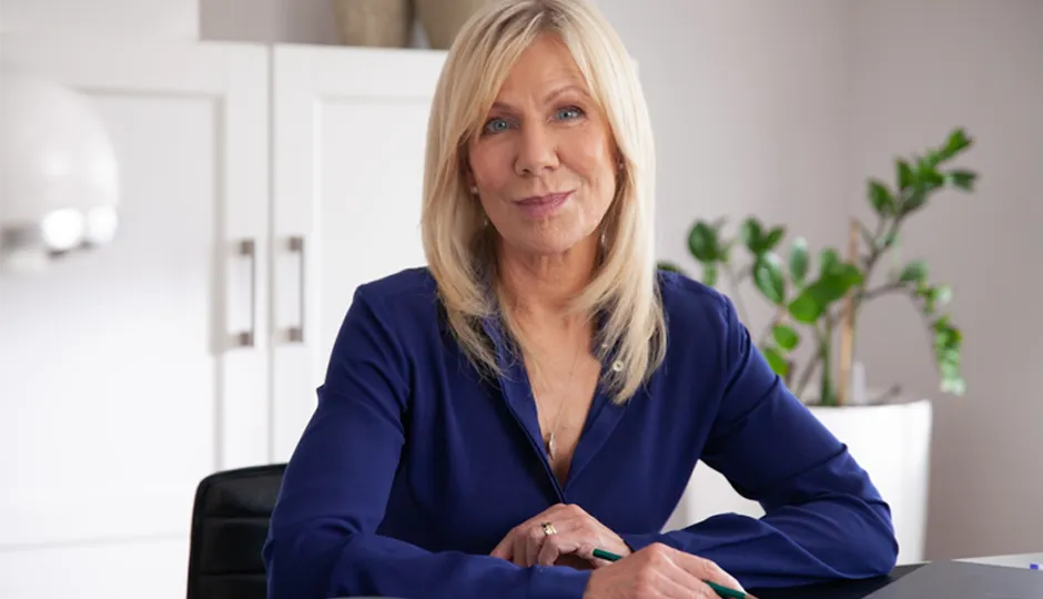 Ulrike von der Groeben sitzt an dem Schreibtisch und schaut in die Kamera bei einer Werbefilmproduktion für TV Werbung.